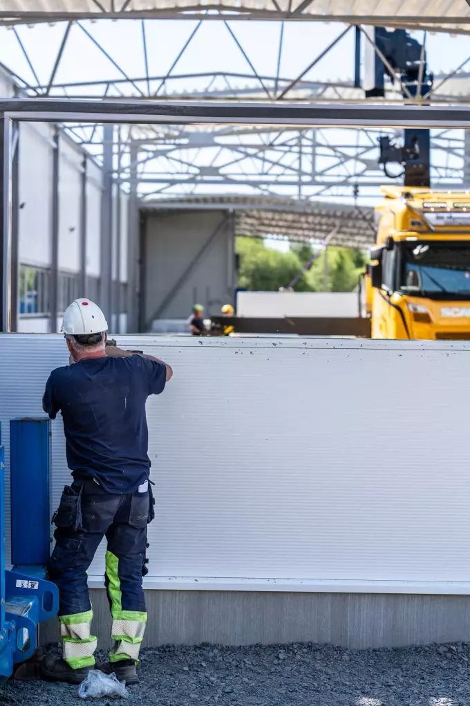 Bauarbeiter montiert Wandpaneele während der Erweiterung der VEAB-Produktionsräume in Hässleholm.
